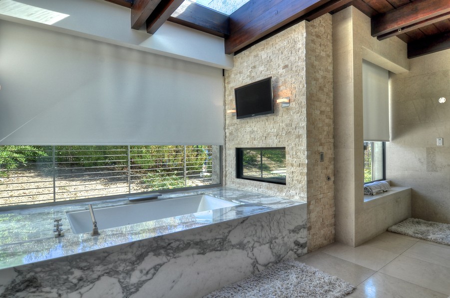 Luxury bathroom with motorized roller shades and a water-resistant TV display connected to the high-speed Wi-Fi.